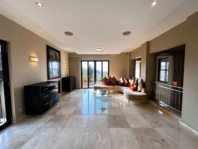 Spacious living room featuring polished marble flooring, recessed lighting, and large glass doors leading to an outdoor area, creating a bright and open atmosphere.