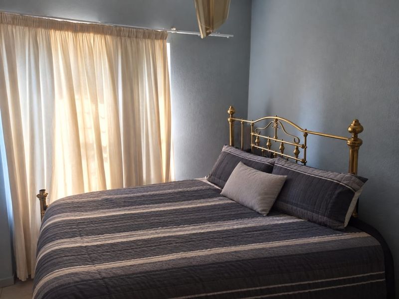 A bedroom featuring blue walls and a curtain rail, providing a functional space for rest.