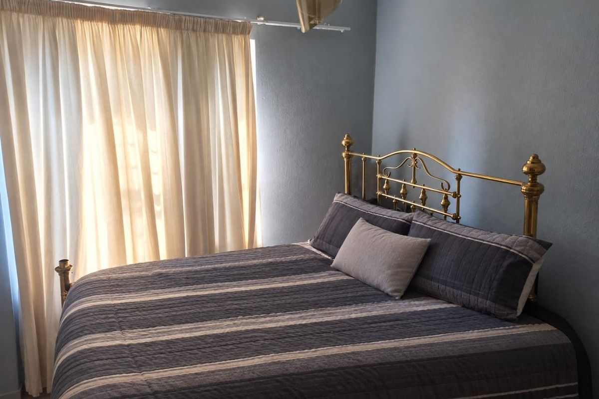 A bedroom featuring blue walls and a curtain rail, providing a functional space for rest.