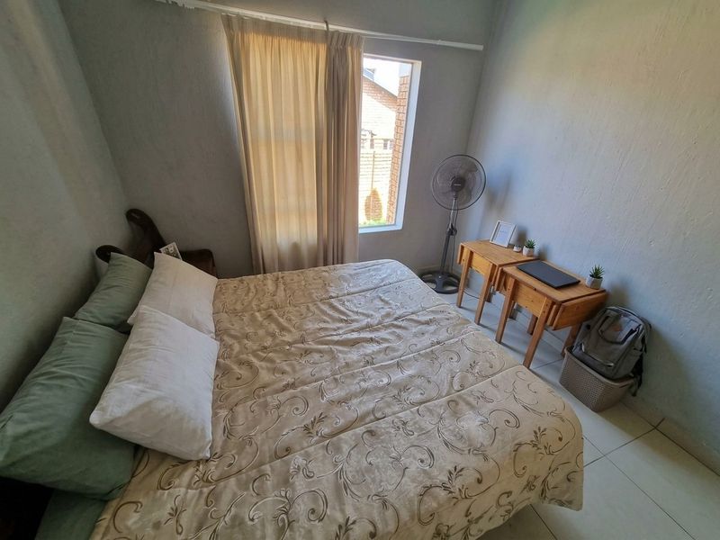 A functional bedroom featuring tiled flooring and a window with a curtain rail, providing a neutral space ready for personalization.