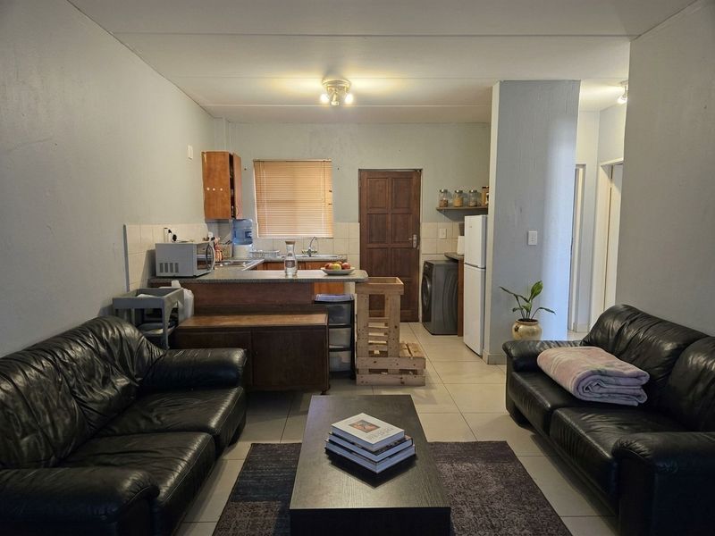 Open plan living area featuring a functional kitchen with built-in cabinetry, tiled flooring, and a breakfast counter, seamlessly connected to the lounge space.