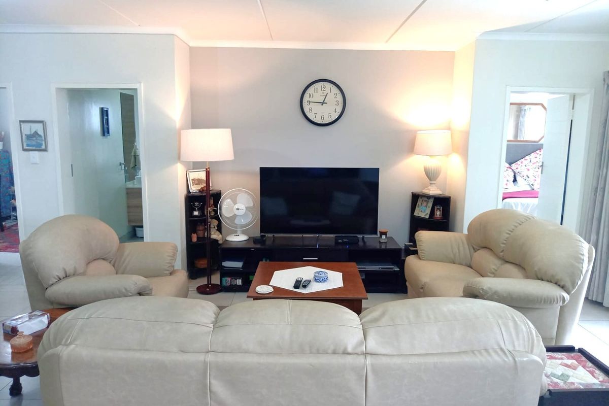 A comfortable living room featuring tiled flooring and neutral wall finishes, providing a functional space with access to adjacent rooms.