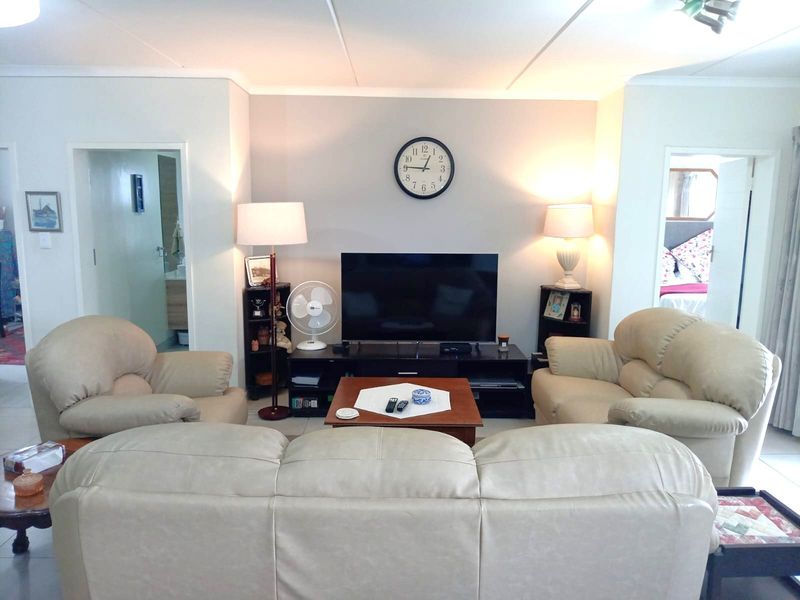 A comfortable living room featuring tiled flooring and neutral wall finishes, providing a functional space with access to adjacent rooms.
