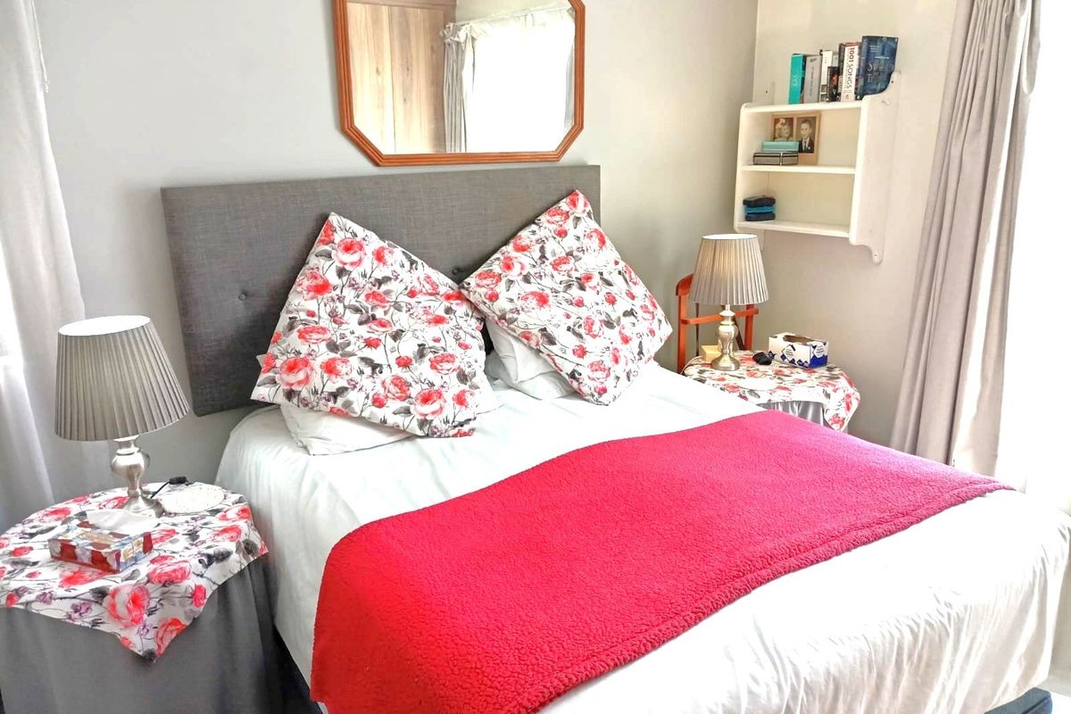 A cozy bedroom featuring neutral wall tones and built-in wall shelving, providing a functional and comfortable sleeping space.