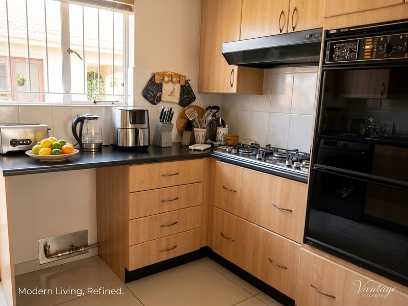 Functional kitchen featuring light wood-finish cabinetry, dark countertops, a gas hob, and a built-in oven with an integrated extractor fan.