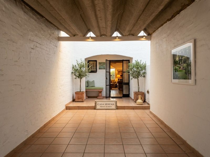 A covered entrance area featuring tiled flooring, white brick walls, and a corrugated roof, leading into the main living space.