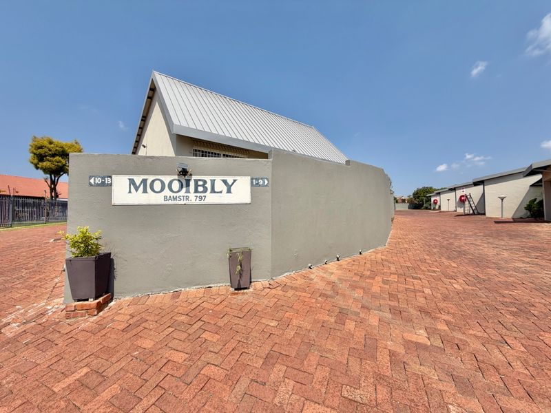 Entrance view of the Mooibly townhouse complex featuring a brick paved driveway and a prominent boundary wall.