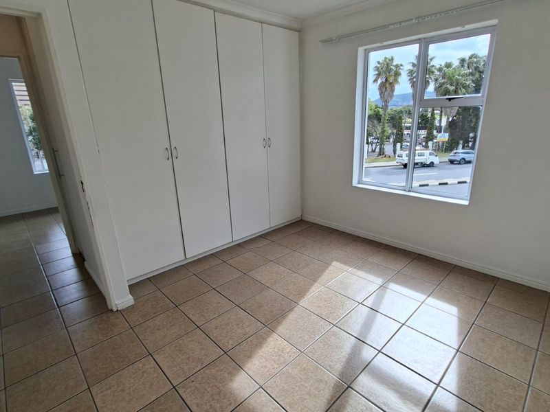 A bright, empty bedroom featuring neutral tiled flooring and built-in cupboards, offering a clean canvas for personalization.