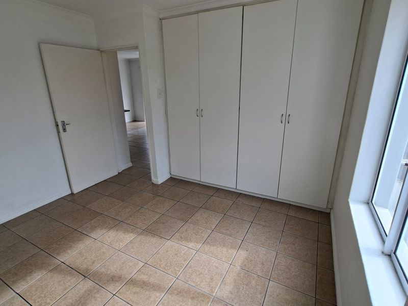 A bright, empty bedroom featuring neutral tiled flooring and ample built-in cupboard storage, offering a clean canvas for personalization.