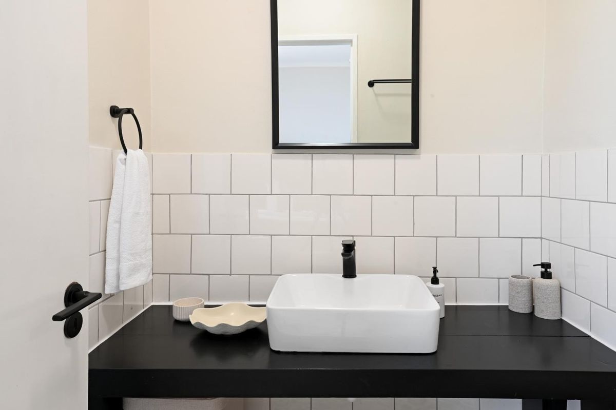 A modern bathroom vanity featuring a white vessel sink, black faucet, and contrasting black countertop with a clean white subway tile backsplash.