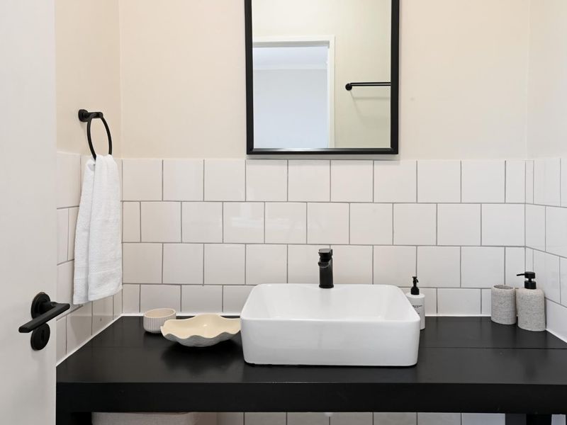 A modern bathroom vanity featuring a white vessel sink, black faucet, and contrasting black countertop with a clean white subway tile backsplash.