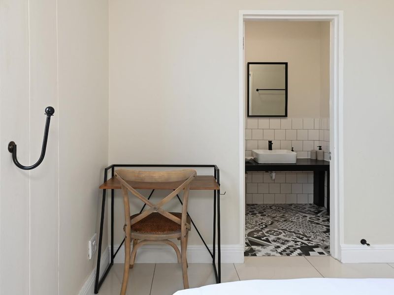 A bedroom featuring a wall-mounted hook and an open doorway leading to an en-suite bathroom with a modern vessel sink and patterned floor tiles.