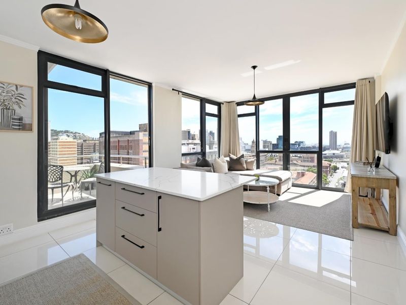 Modern open-plan living area featuring a sleek kitchen island, high-gloss tiled floors, and expansive floor-to-ceiling windows offering panoramic city views.