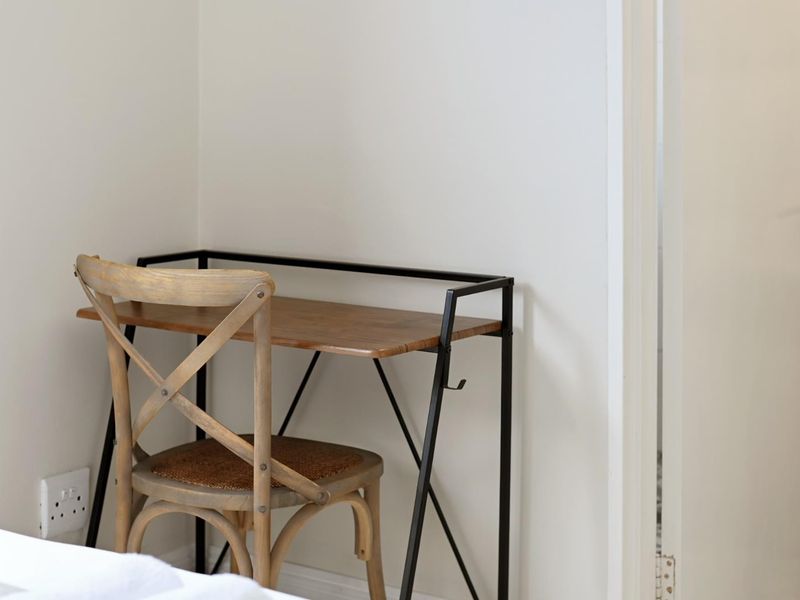 A corner view of a bedroom featuring neutral walls, a standard door, and a wall-mounted electrical outlet.