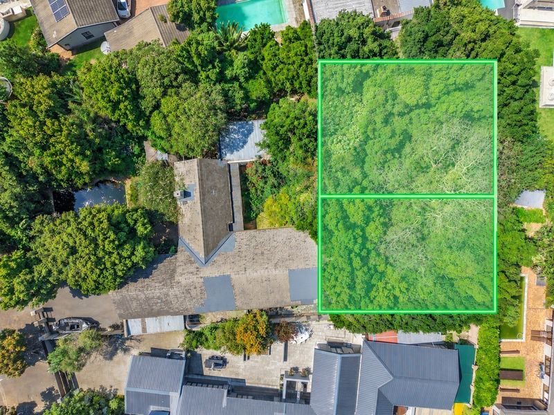 Aerial view of the property showcasing the main dwelling, tiled roof, swimming pool, paved patio area, and extensive mature garden landscaping.