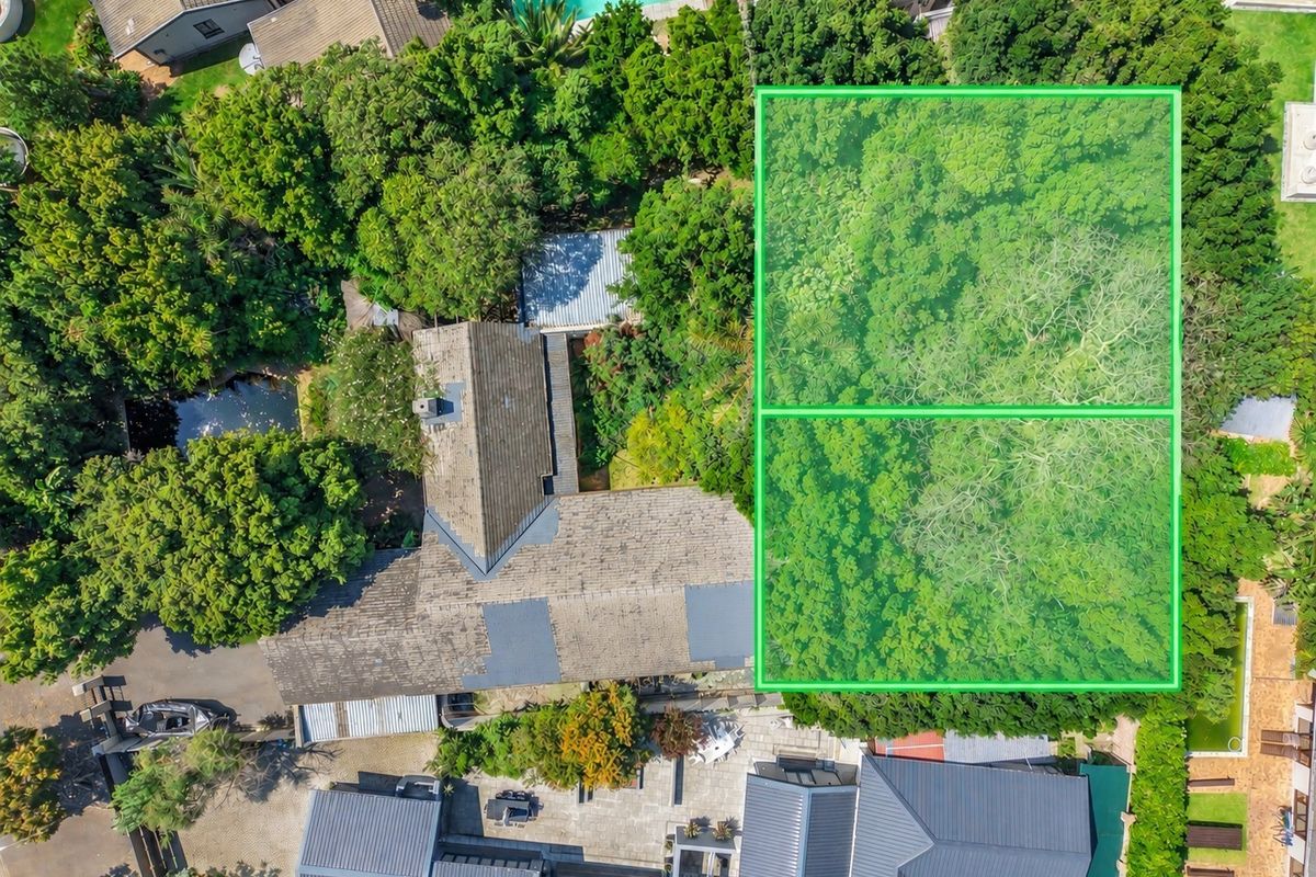 Aerial view of the property showcasing the main dwelling, tiled roof, swimming pool, paved patio area, and extensive mature garden landscaping.