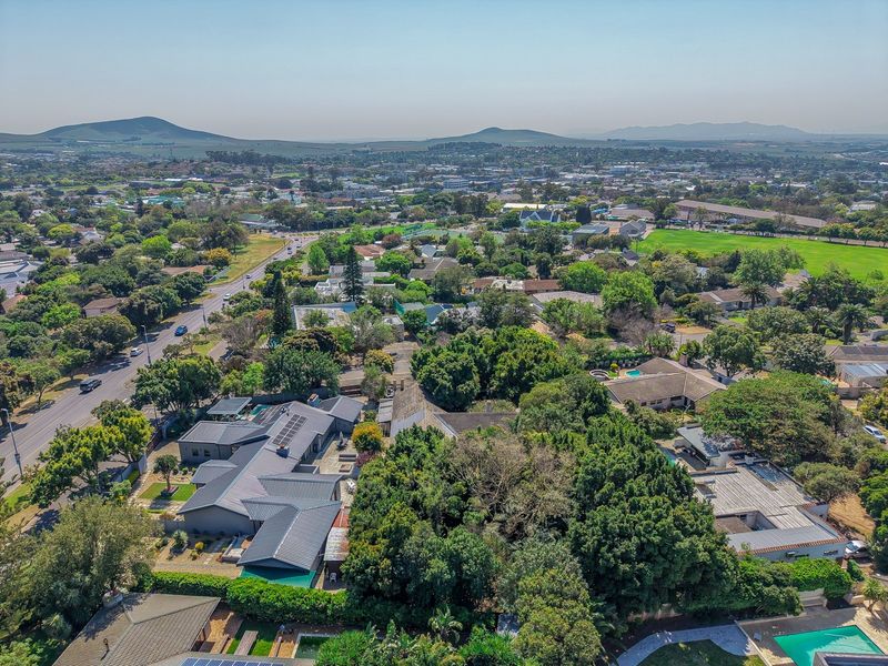 Aerial view of the property showing the residential layout, surrounding neighborhood, mature trees, and proximity to local amenities.