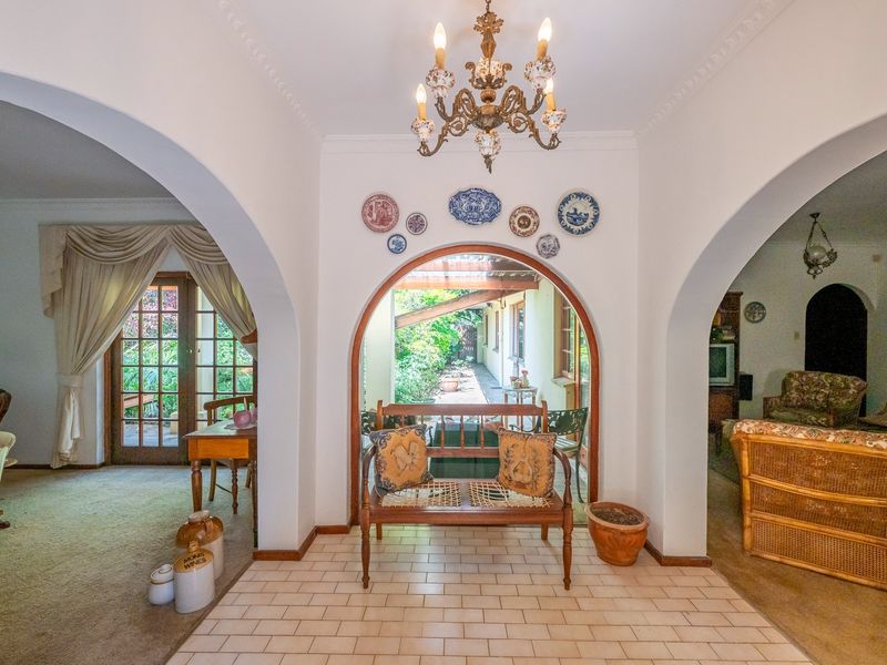 Welcoming entrance hall featuring classic arched architectural details, ceramic tile flooring, and an elegant chandelier, providing a central transition point between living areas.