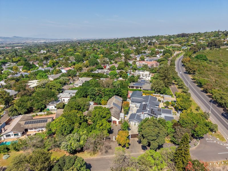 An aerial view of the property showing the roof structure, solar panel installations, driveway, and surrounding landscaped grounds within the neighborhood.