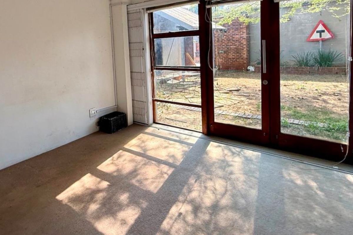 An empty living room featuring carpet flooring and large sliding glass doors providing direct access to the rear garden area.