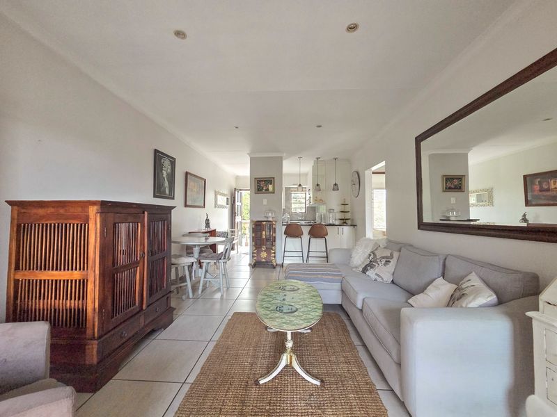 Open-plan living and kitchen area featuring tiled flooring, recessed lighting, and a breakfast counter, creating a functional and connected living space.