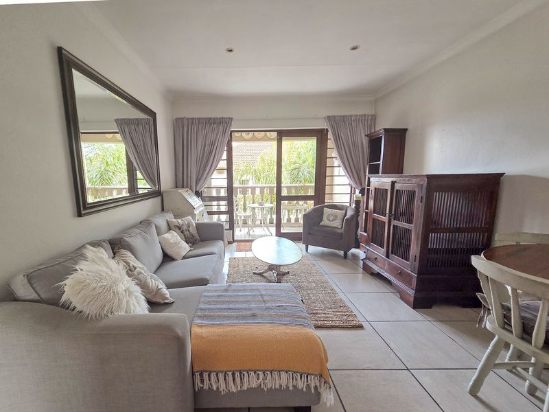 Open-plan living area featuring tiled flooring, recessed lighting, and direct access to a private balcony through sliding glass doors.