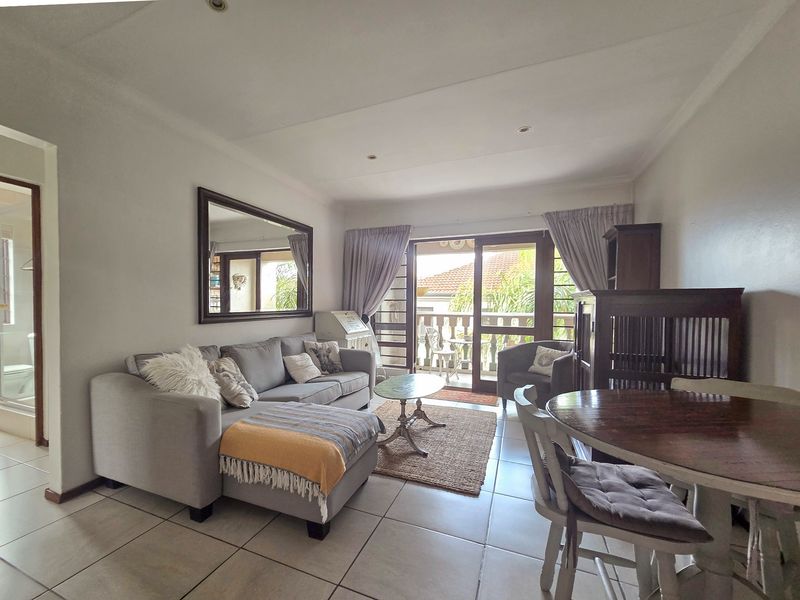 Open-plan living and dining area featuring tiled flooring, recessed lighting, and sliding glass doors providing access to a private balcony.