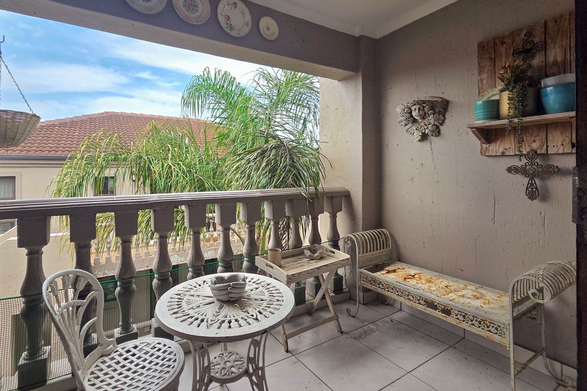 A covered balcony featuring a classic balustrade and tiled flooring, offering an outdoor space with views of the surrounding residential area.