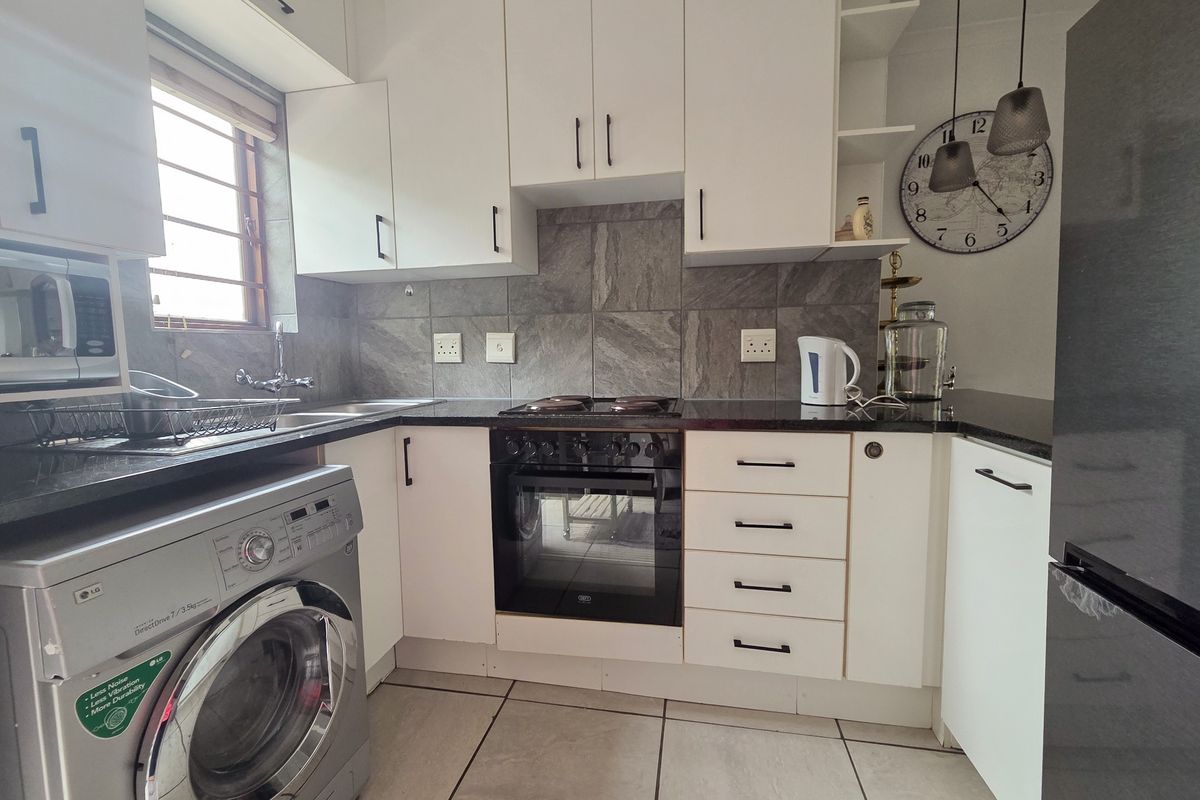 A well-maintained kitchen featuring white cabinetry, granite countertops, a tiled backsplash, and integrated appliances including an oven and hob.
