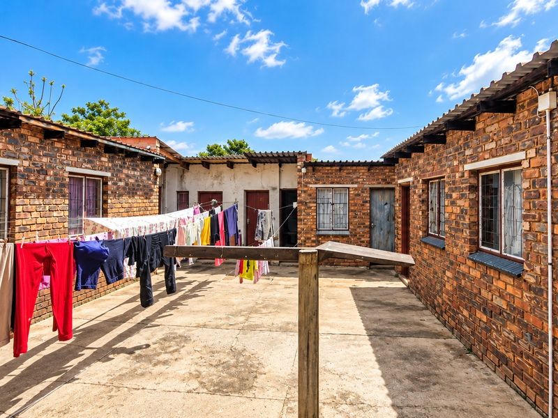 A rear courtyard area featuring face brick construction, concrete paving, and multiple access points to the building units.
