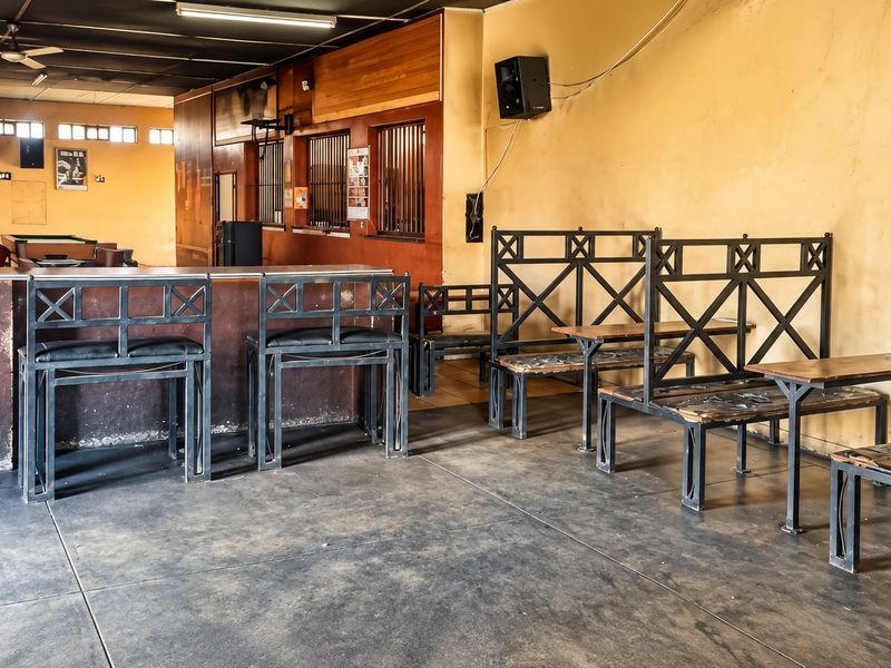 Commercial bar area featuring a built-in counter, security window bars, and tiled flooring, suitable for renovation or interior design updates.
