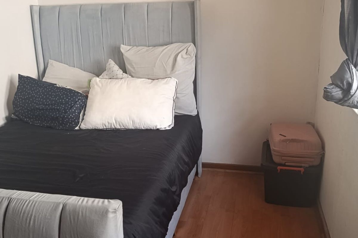 A compact bedroom featuring laminate flooring and a window, providing a functional space for rest.