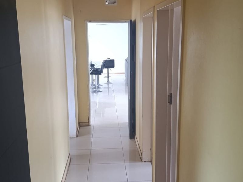 A functional hallway with tiled flooring connecting various rooms, featuring neutral wall paint and standard internal door frames.