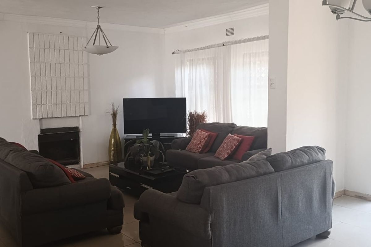 Spacious living room featuring a fireplace, tiled flooring, and a security gate, offering a functional layout with potential for modern updates.