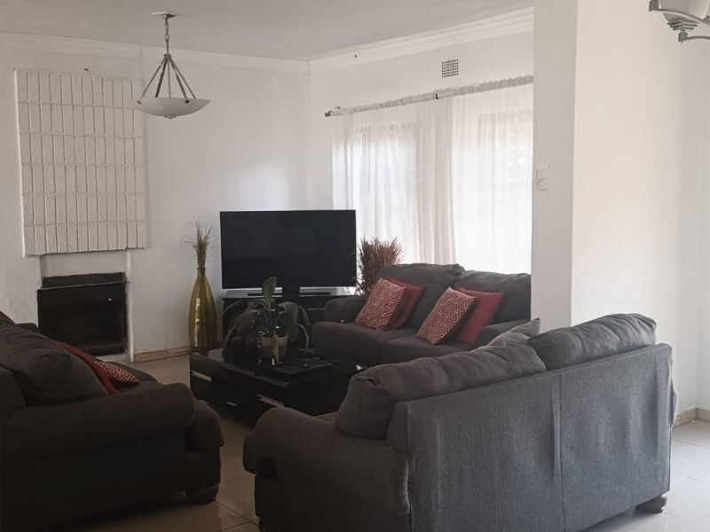Spacious living room featuring a fireplace, tiled flooring, and a security gate, offering a functional layout with potential for modern updates.