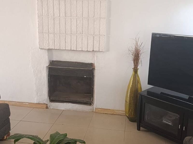 Living room featuring a built-in fireplace with visible wall plaster damage and tiled flooring throughout.