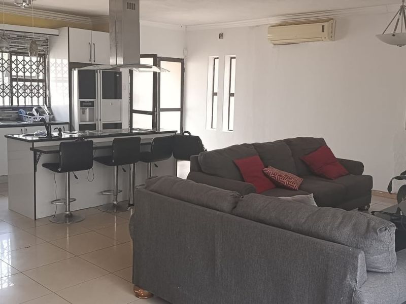 Open-plan living area featuring a modern kitchen with island, tiled flooring, and a fireplace, creating a functional and connected space for daily living.