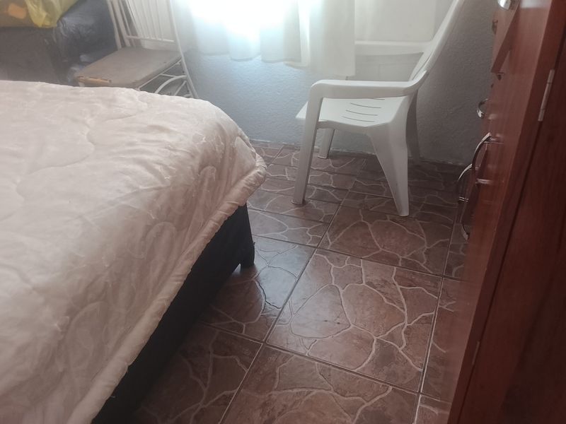 A bedroom featuring tiled flooring and natural light from a window.