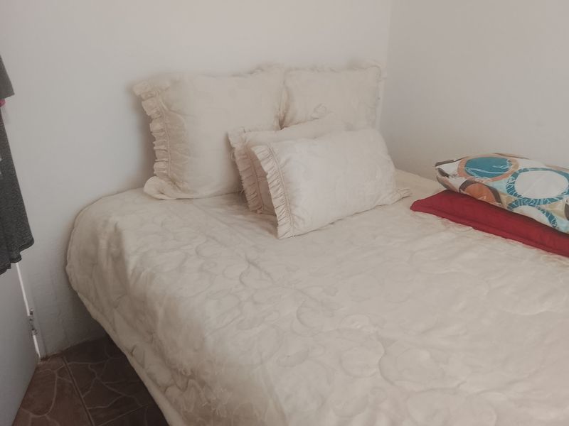 A simple bedroom space featuring tiled flooring and neutral wall finishes.