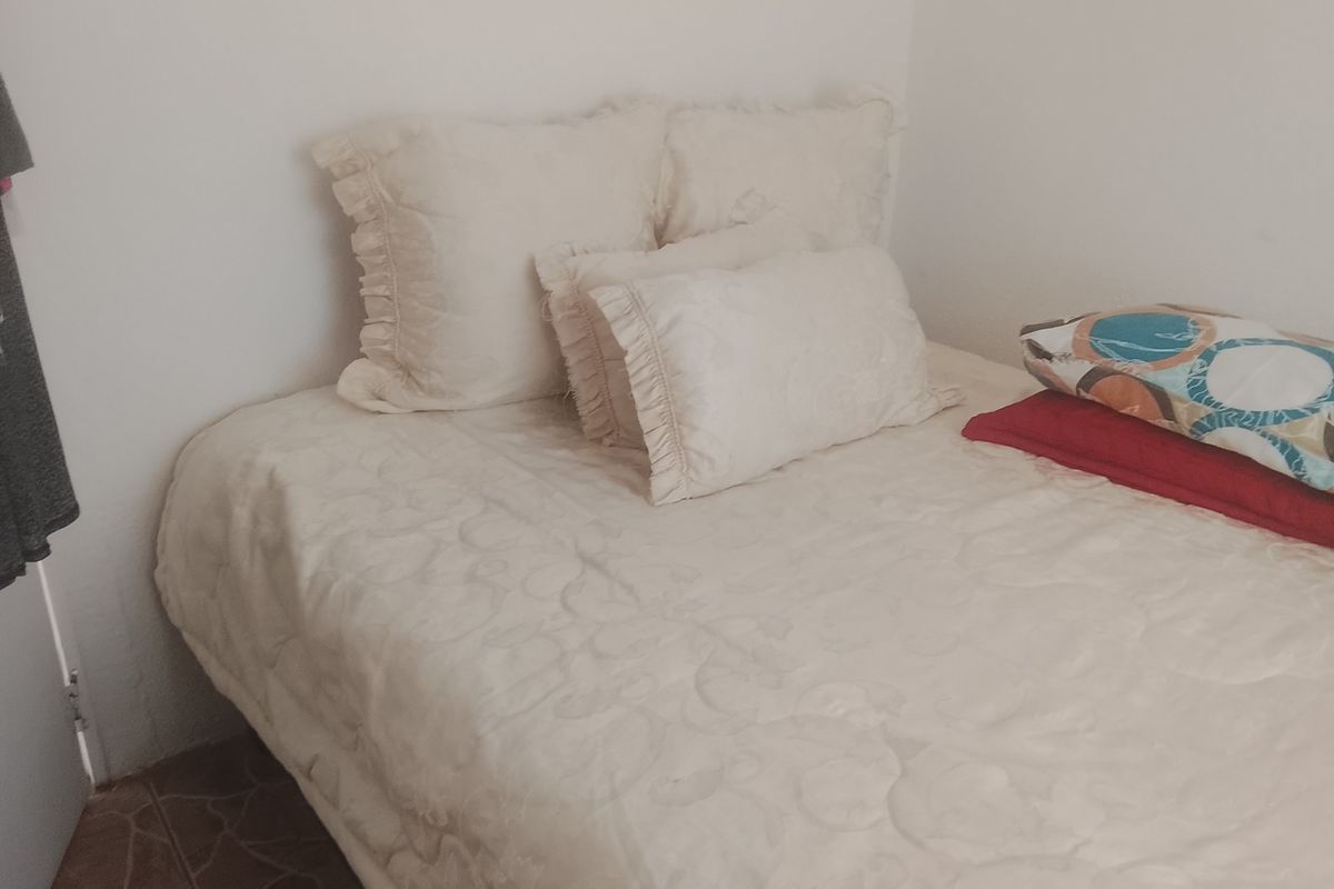 A simple bedroom space featuring tiled flooring and neutral wall finishes.