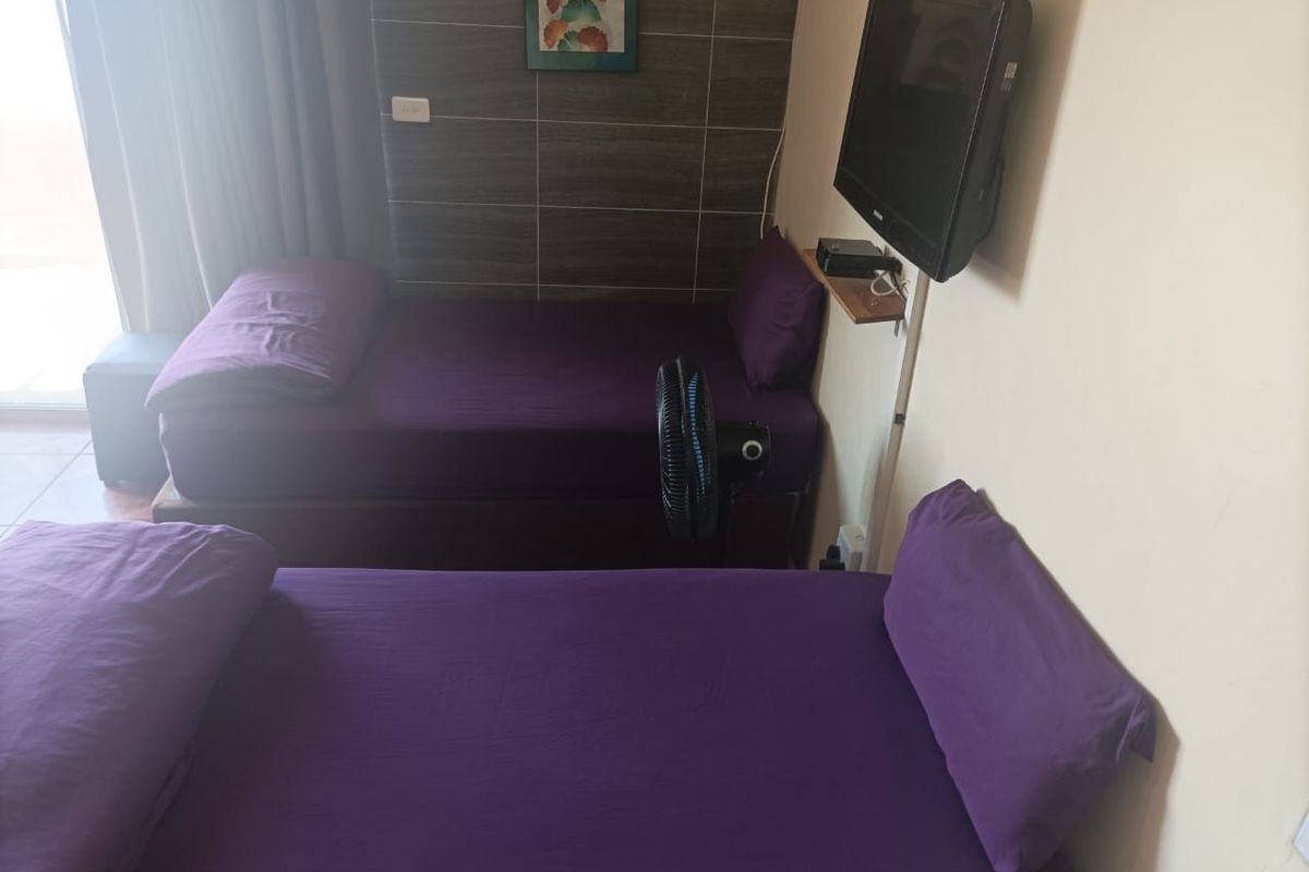A bedroom featuring a tiled accent wall and wall-mounted television, providing a functional sleeping space.