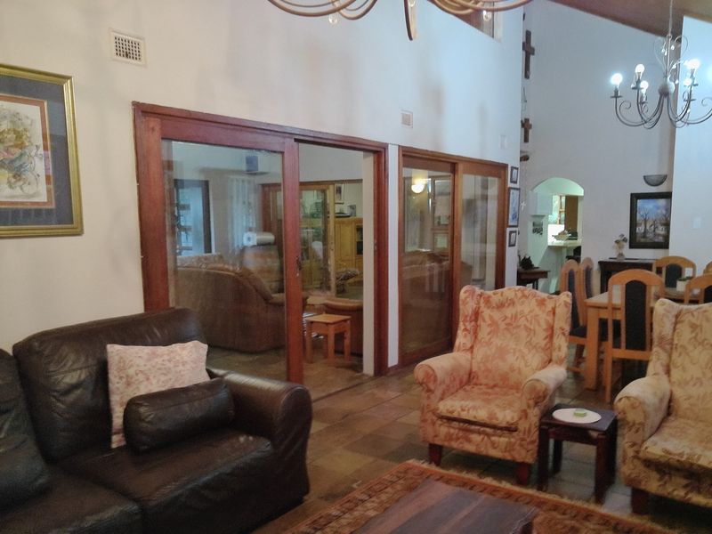 Spacious living area featuring high vaulted ceilings, tiled flooring, and large sliding glass doors that provide a view into an adjacent room.