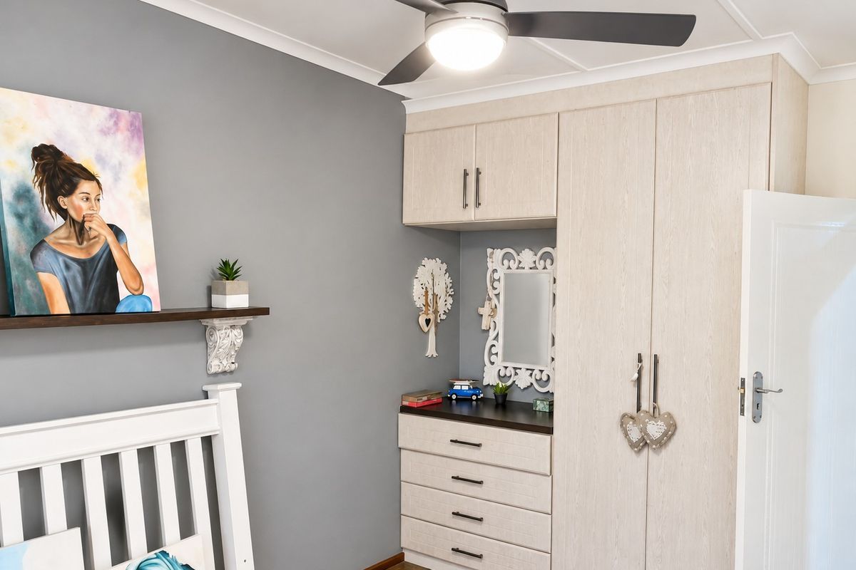 A well-maintained bedroom featuring built-in cabinetry with integrated vanity, modern ceiling fan, and durable tiled flooring.