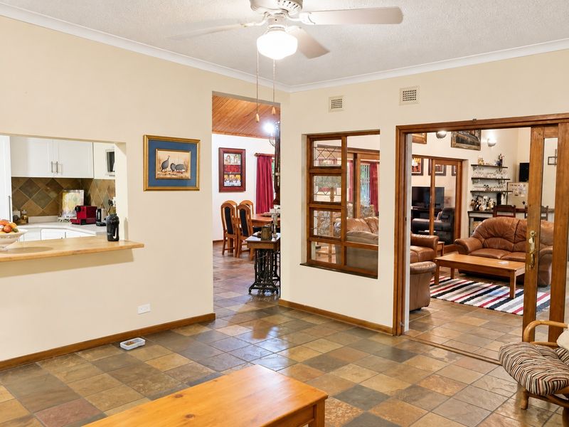 Open plan living area featuring tiled flooring, a ceiling fan, and views through to the kitchen and adjacent living spaces.