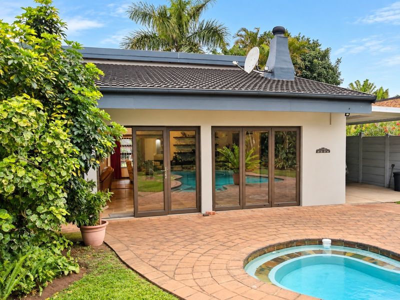 Rear view of the property featuring a paved patio area, swimming pool, and large aluminium sliding doors providing access to the interior living space.