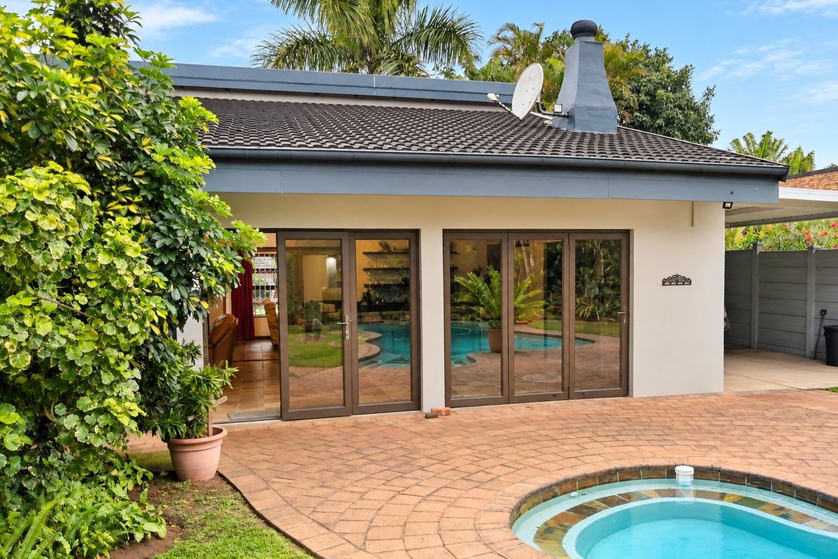 Rear view of the property featuring a paved patio area, swimming pool, and large aluminium sliding doors providing access to the interior living space.