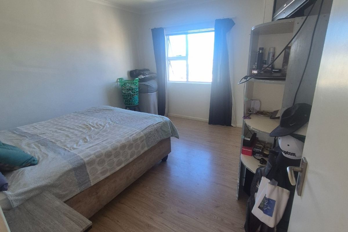 A standard bedroom featuring laminate flooring, a central ceiling light, and a window providing natural light.