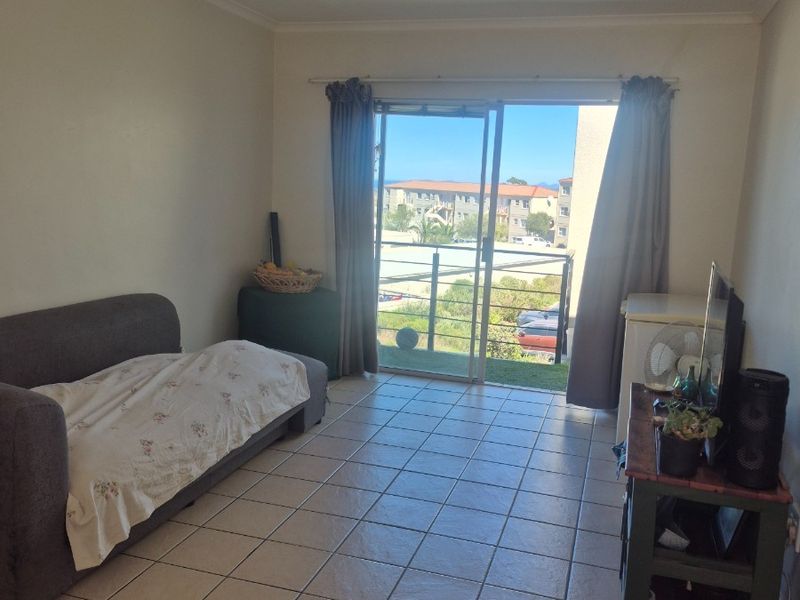 A living room featuring tiled flooring and a sliding glass door that provides access to a balcony with exterior views.