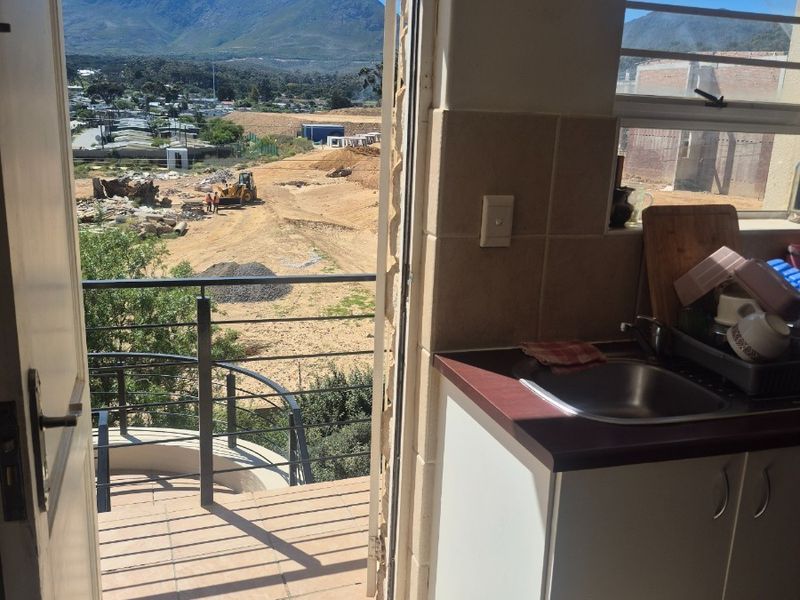 Compact kitchen area featuring built-in cabinetry and sink, with direct access to a balcony offering scenic mountain and landscape views.