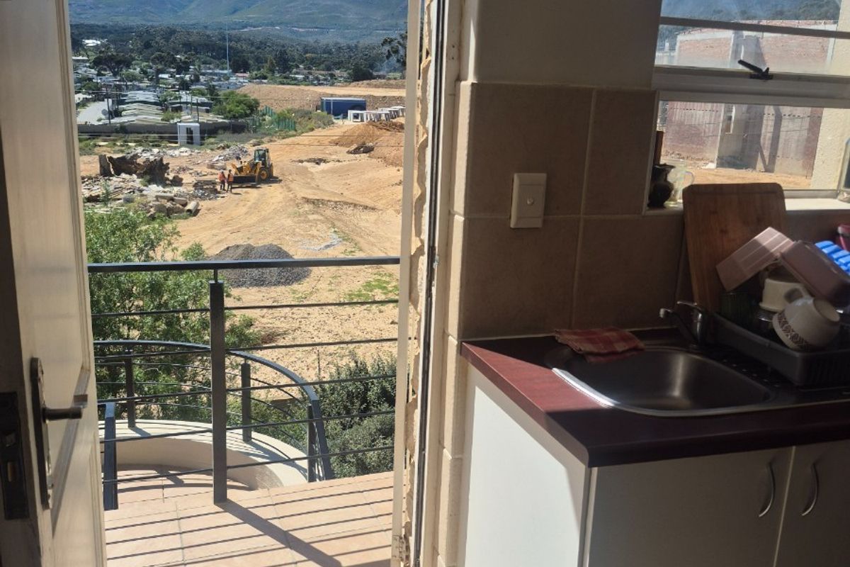 Compact kitchen area featuring built-in cabinetry and sink, with direct access to a balcony offering scenic mountain and landscape views.